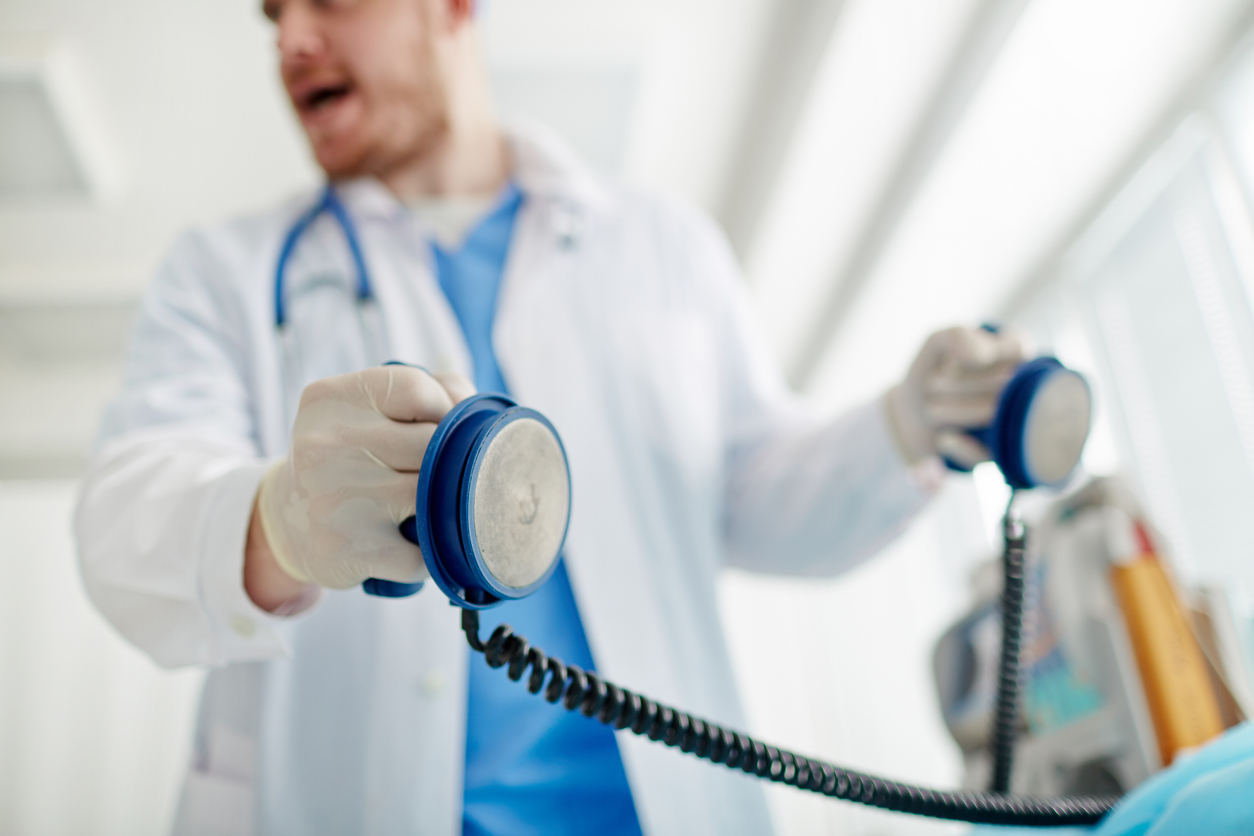 Doctor holding defibrallator in hands going to send a shock