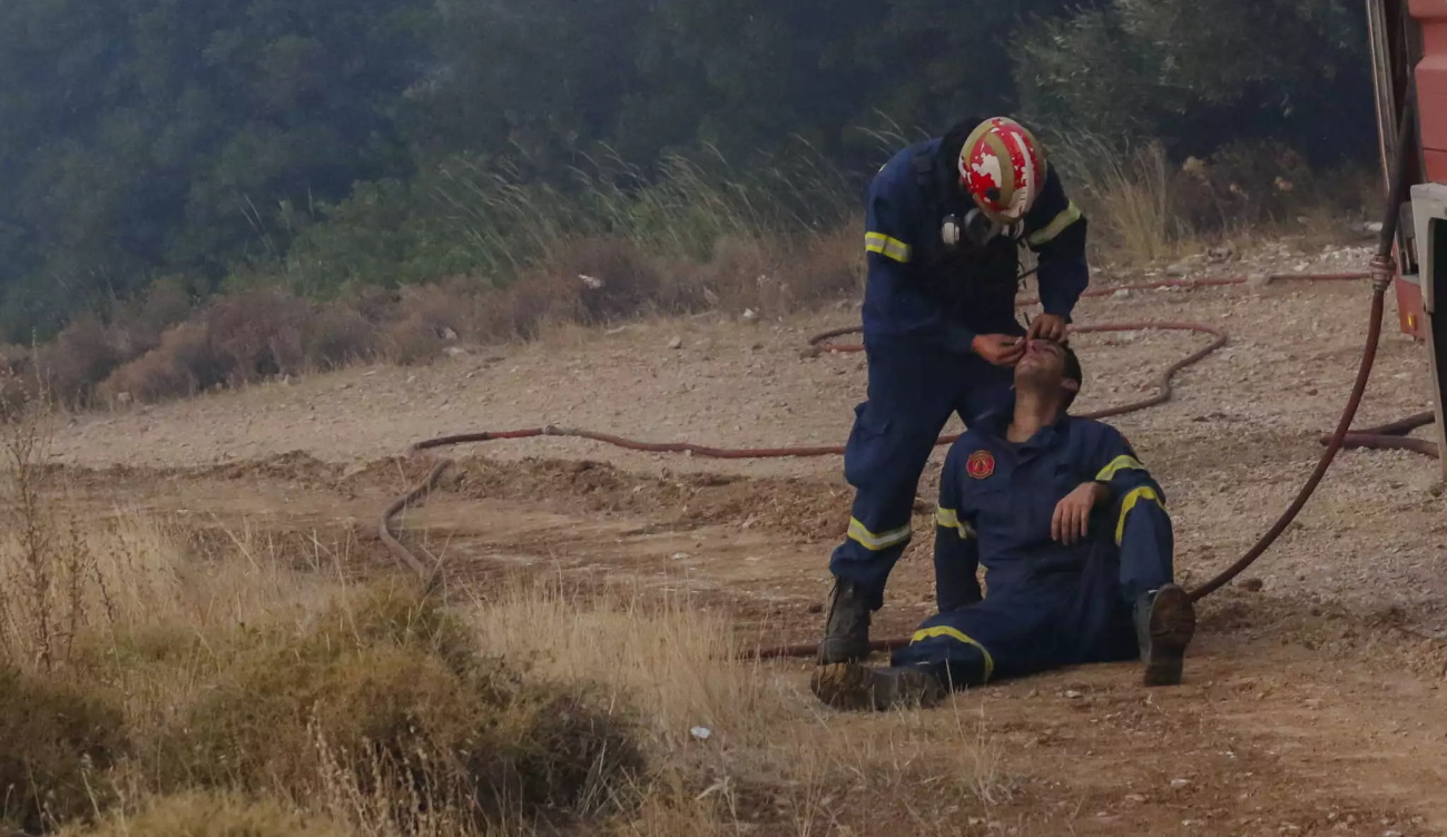 Φωτιά στην Πάρνηθα: Πυροσβέστης φροντίζει συνάδελφο στο πύρινο μέτωπο
